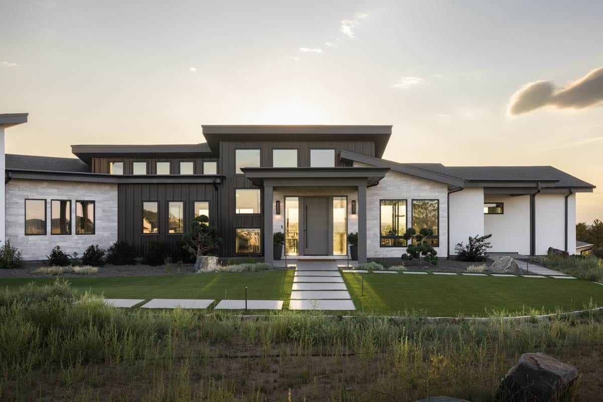 Modern house plan exterior with layered rooflines, stone and vertical siding, and expansive windows.