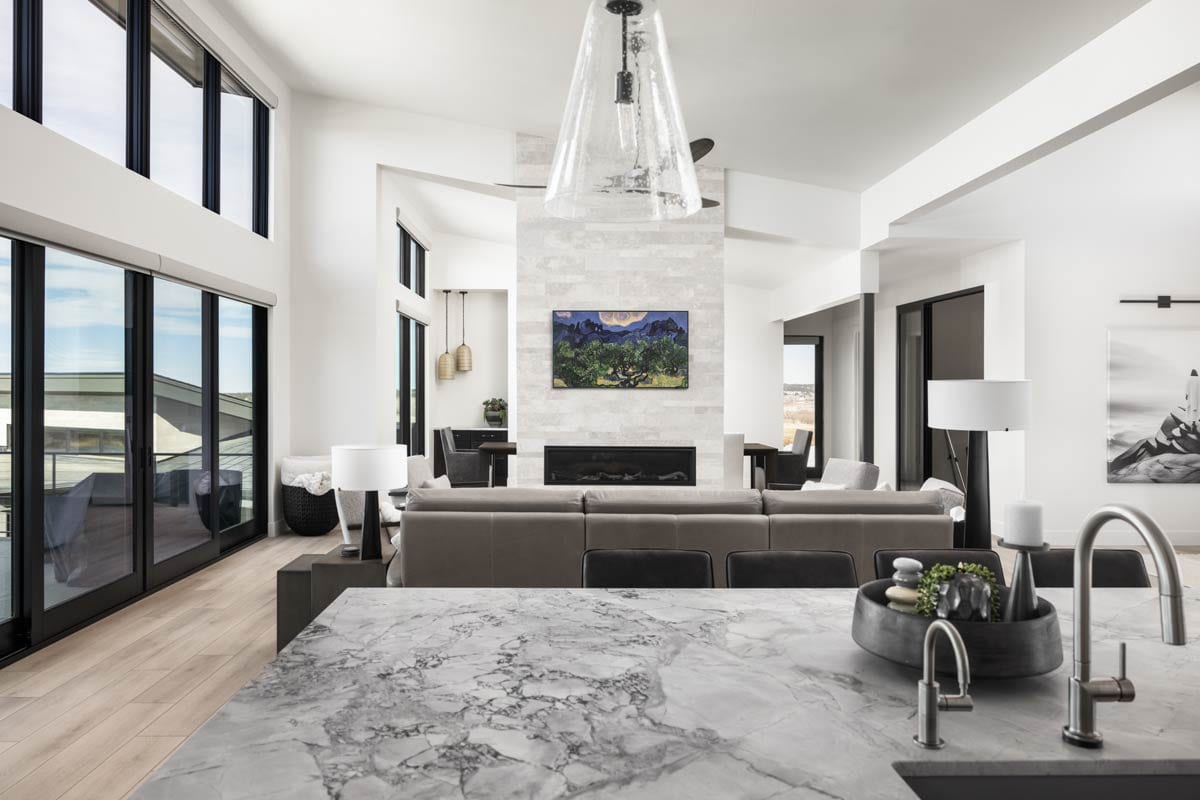 Open-concept living area with a large sectional sofa, stone fireplace, and floor-to-ceiling windows.