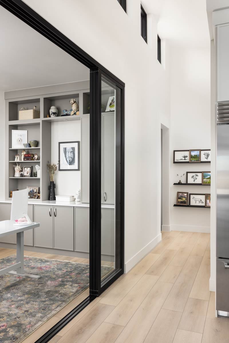 Modern interior hallway with built-in shelving, a sliding glass door, and upper clerestory windows.