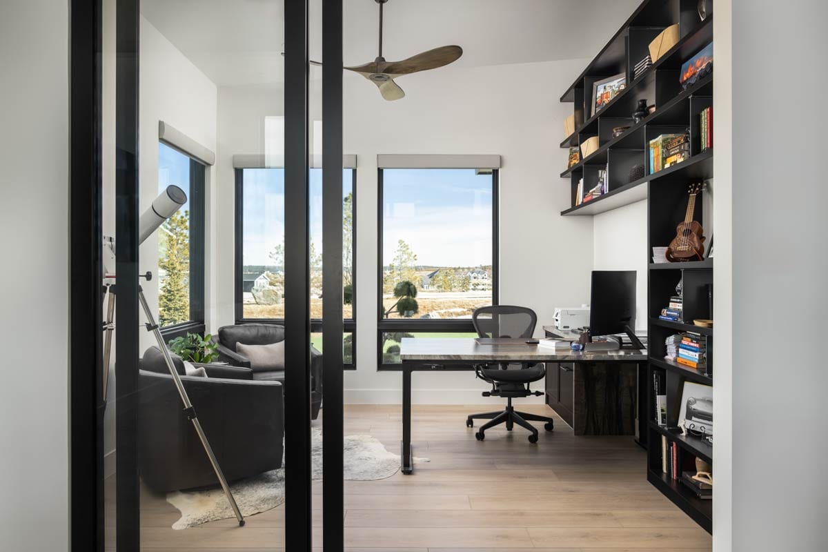 Home office with desk, computer, chairs, telescope, and built-in shelving units.